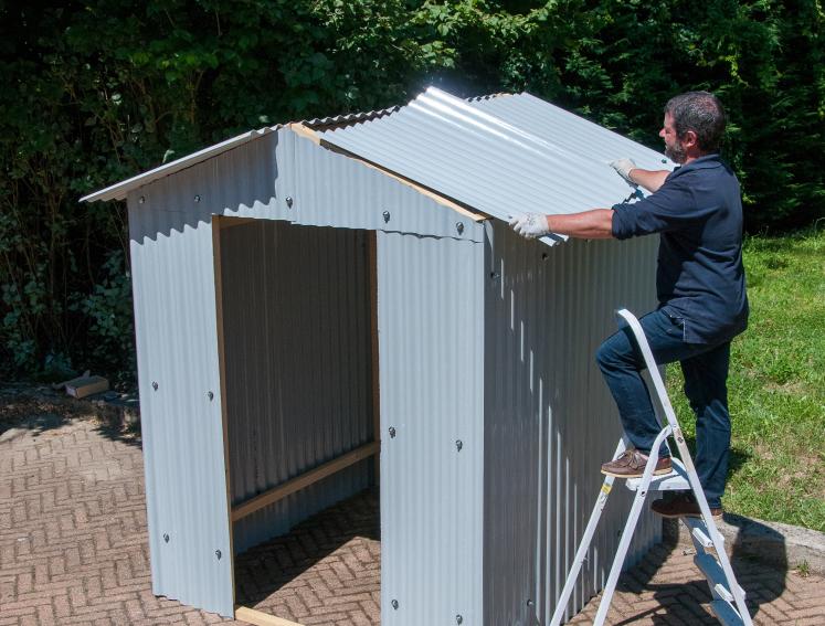 Man building small workshop shed with ONDUPLAST COLOUR roof sheets