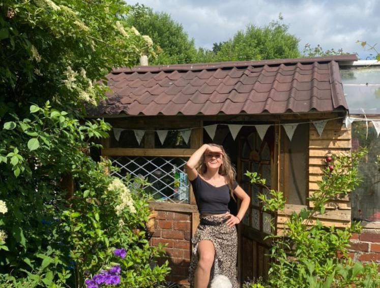 Woman in front of allotment shed built with Onduline ONDUVILLA tile look roofing