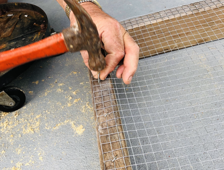 Man hammering in nails to timber frame 